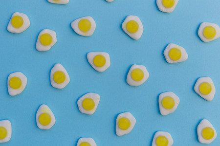 Fried eggs candy sweets on bright blue background