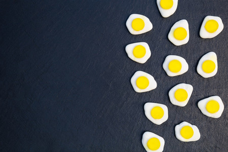 Fried eggs candy sweets on dark background with copy space