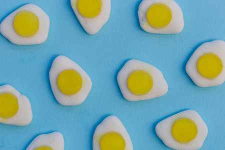 Fried eggs candy sweets on bright blue background
