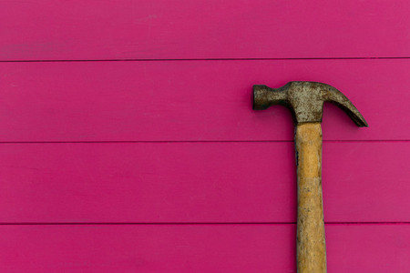 Old hammer on pink wood texture background