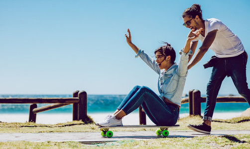 Loving couple playing on skateboard near the beach