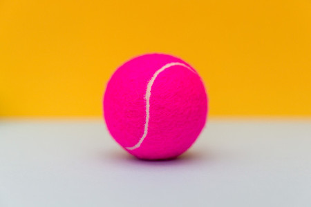 Pink tennis ball on yellow background