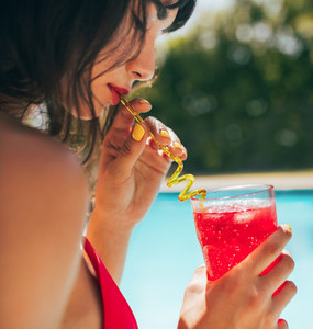 Woman drinking cocktail at the poolside