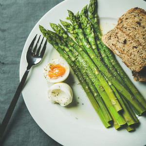 Cooked asparagus with soft boiled egg and grilled bread square crop