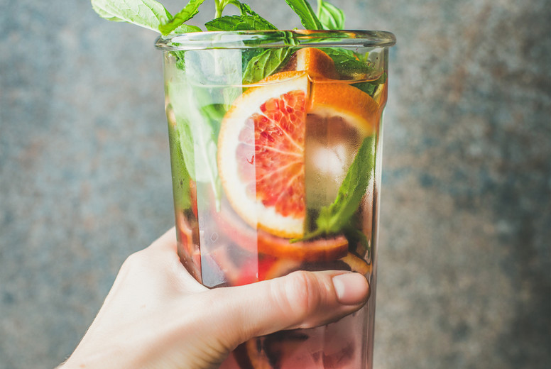 Womans hand holding glass of blood orange citrus lemonade