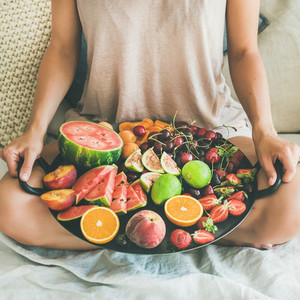 Young girl holding tray full of fresh fruits square crop