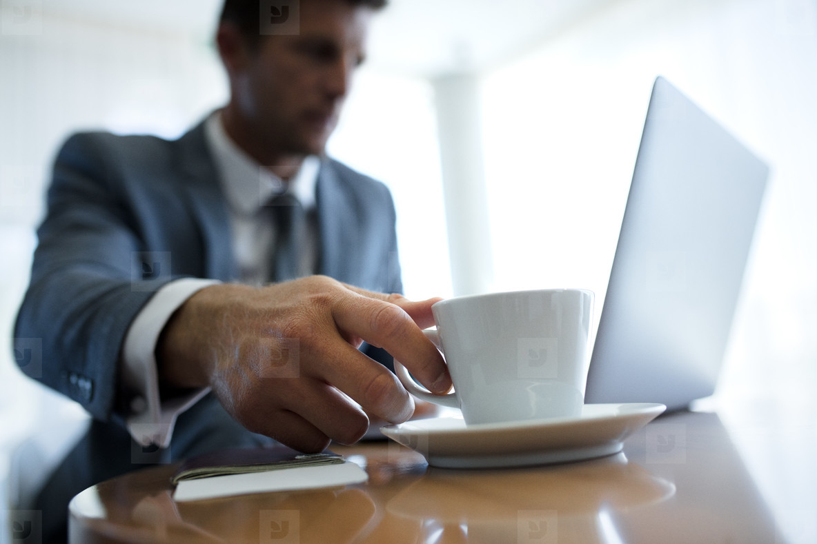 Businessman in office lobby picking cup of coffee