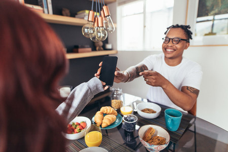 Couple at breakfast table with phone