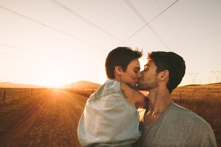 Woman kissing a man outdoors on a road trip