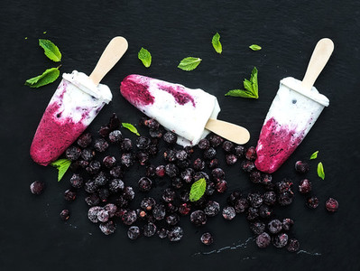 Black currant milk ice creams or popsicles with frozen black currant and mint