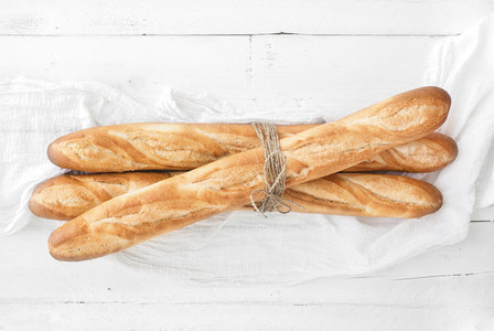 Freshly baked French baguettes on white wooden table