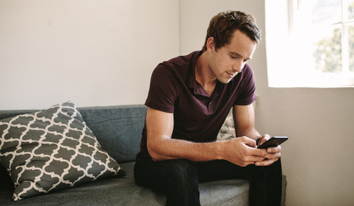 Freelancer looking at mobile phone sitting at home