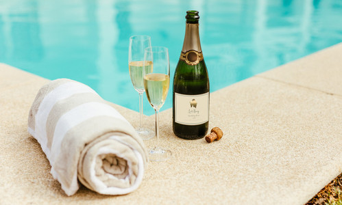 Sparkling wine and towel by the pool