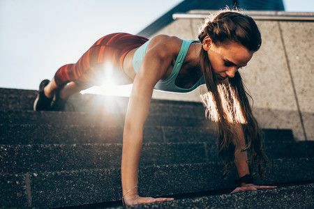 Sportswoman doing push ups on steps