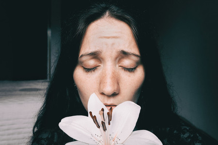 a girl with a white lily and eyes closed worried