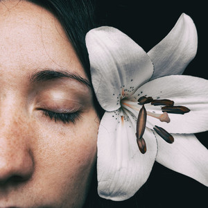 half of a girls face with a white lily and closed eyes