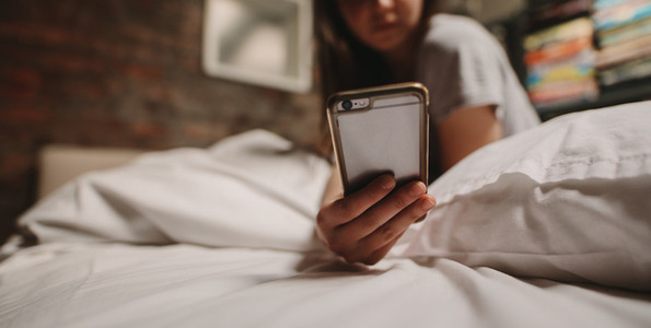 Woman looking at mobile phone sitting on bed
