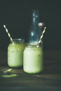 Refreshing iced coconut matcha latte drink in jars  wooden table