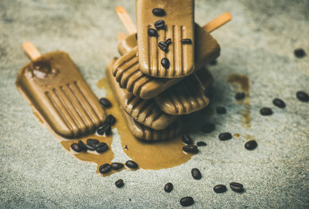 Flatlay of melting coffee latte popsicles with beans