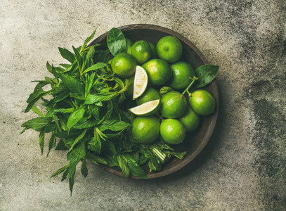 Flatlay of fresh limes and mint in wooden plate