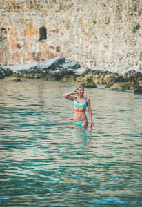 Young woman tourist enjoying sea at beach near fortress wall
