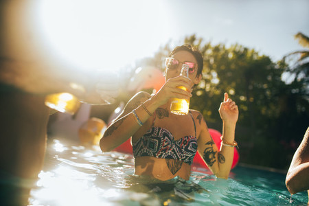 Woman having beer with friends in pool party