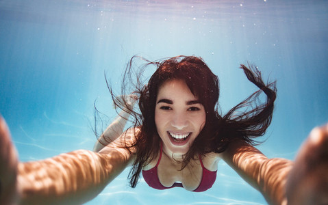 Woman swimming underwater and taking selfie
