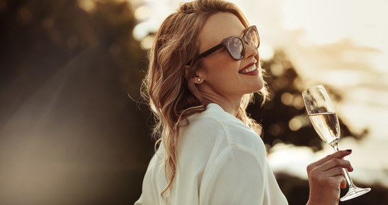 Smiling woman in sunglasses drinking wine