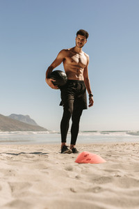 Man doing fitness training at the beach using a medicine ball