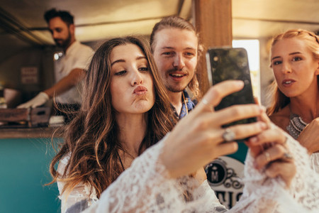 Beautiful woman taking selfie with friends