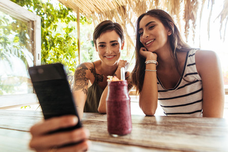 Friends taking selfie with a smoothie on the table