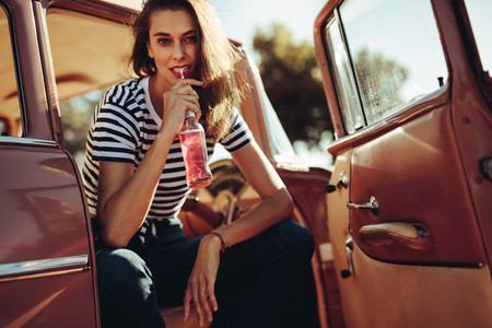 Beautiful woman drinking soft drinking in the car