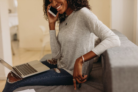 Woman managing business from home with mobile phone and laptop