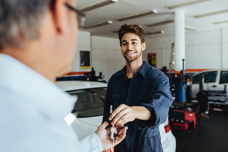 Mechanic giving car keys to customer after servicing