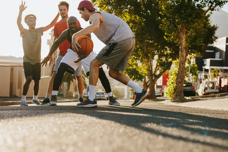 Men playing basketball on street
