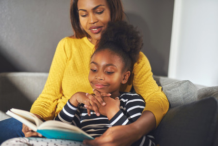 Black mom and daughter reading a book