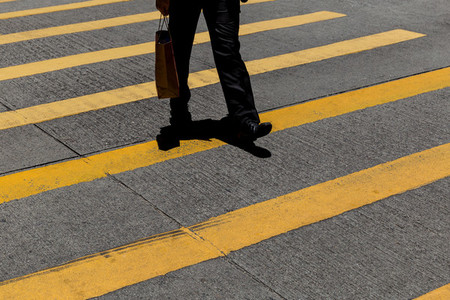 Businessman wearing suit with shopping bag crossing road in Hong