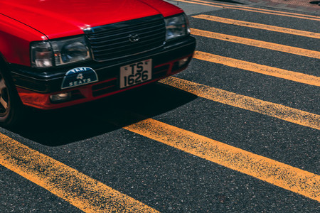 Red taxi car on road crossing in Hong