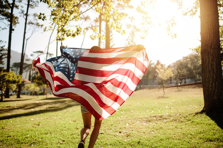 Woman running with american flag in park