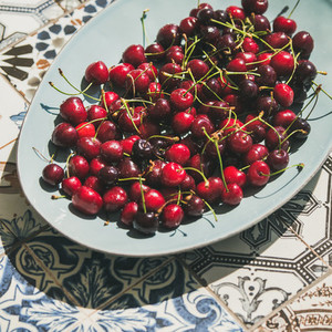 Fresh ripe sweet cherries in plate over oriental ceramic background