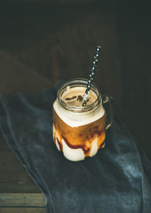 Iced caramel macciato coffee with milk in jar with straw
