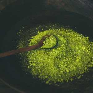 Japanese Matcha green tea powder in dark wooden bowl