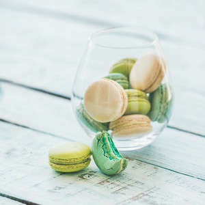 Colorful pastel French macaron biscuits in glass on wooden table