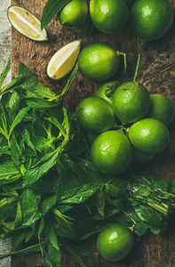 Flatlay of fresh limes and mint on wooden board background