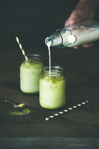 Refreshing iced coconut matcha latte drink in glass jars