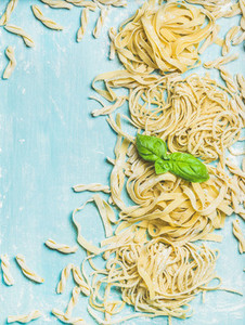 Various homemade fresh Italian pasta with flour and basil