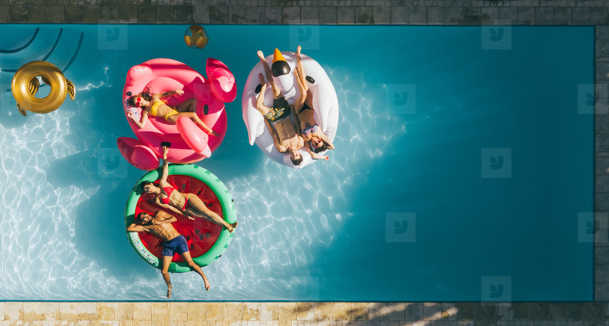 Friends relaxing on inflatable mattresses in pool