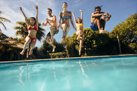 Friends jumping into a swimming pool and having fun