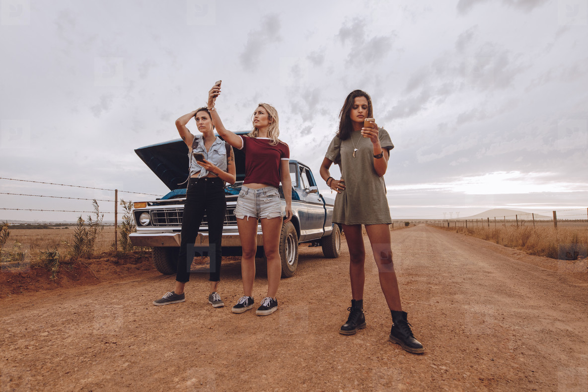 Woman with broken down car in middle of road trip