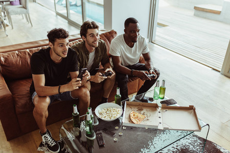 Friends playing video game sitting at home